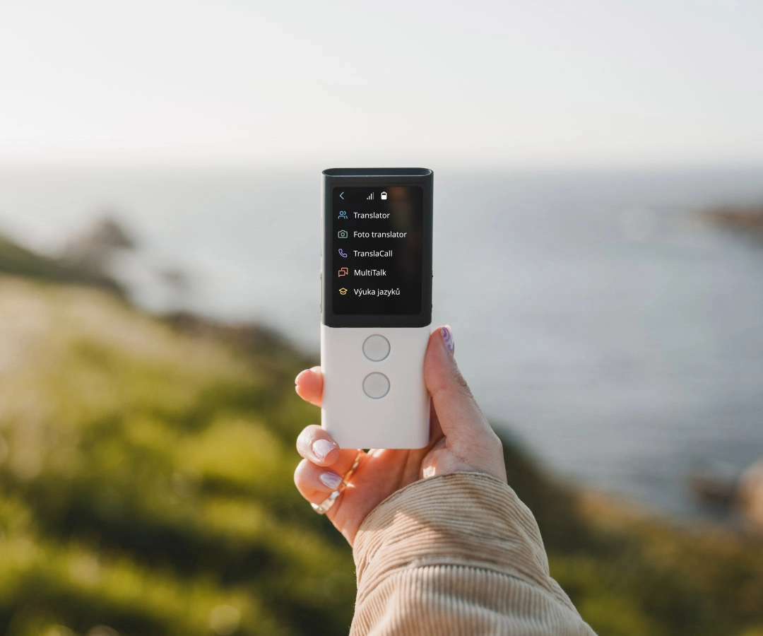 a person stands by the ocean proudly displaying an electronic translator in her hand