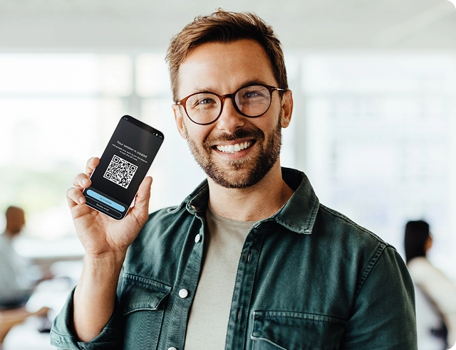 Usmívající se muž držící chytrý telefon zobrazující QR kód pro připojení k Vasco Audience.