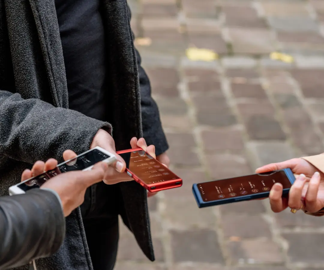 Three friends happily holding their translators, engaged in conversation and sharing moments together. 