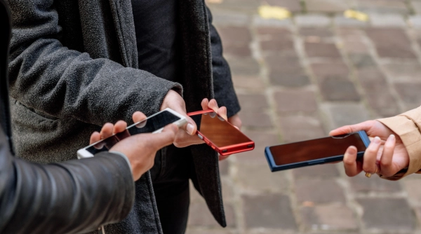 Three people are standing, each holding a translator device in their hands.